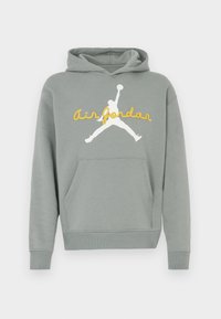 Γκρι φούτερ με κουκούλα από απαλό ύφασμα, με λευκό γραφικό σιλουέτας και κίτρινο κείμενο "Air Jordan" στο μπροστινό μέρος. Περιλαμβάνει τσέπη καγκουρό.