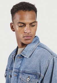 Spijkerjacket in lichtblauw, met een klassieke kraag, twee voorzakken met zilveren knopen en een relaxte pasvorm. Textuurstof.