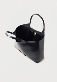 Μαύρη δερμάτινη τσάντα tote με δύο λαβές, εσωτερική τσέπη με χρυσό κούμπωμα και χρυσά διακοσμητικά με λογότυπο στο μπροστινό μέρος, εμφανιζόμενη από μια κορυφαία γωνία.