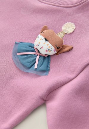 Pull rose avec une applique de poupée renard en tissu, jupe en tulle bleu et accent de couronne dorée, ornée de motifs floraux sur le visage.