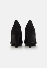 Black suede high-heeled shoes with pointed toes and slim stiletto heels. Smooth texture and minimalistic design.