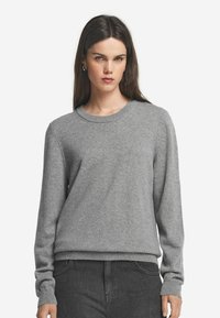 Grauer Pullover aus weichem Material, mit Rundhals, langen Ärmeln und geripptem Saum. Glatte Textur, minimalistisches Design.