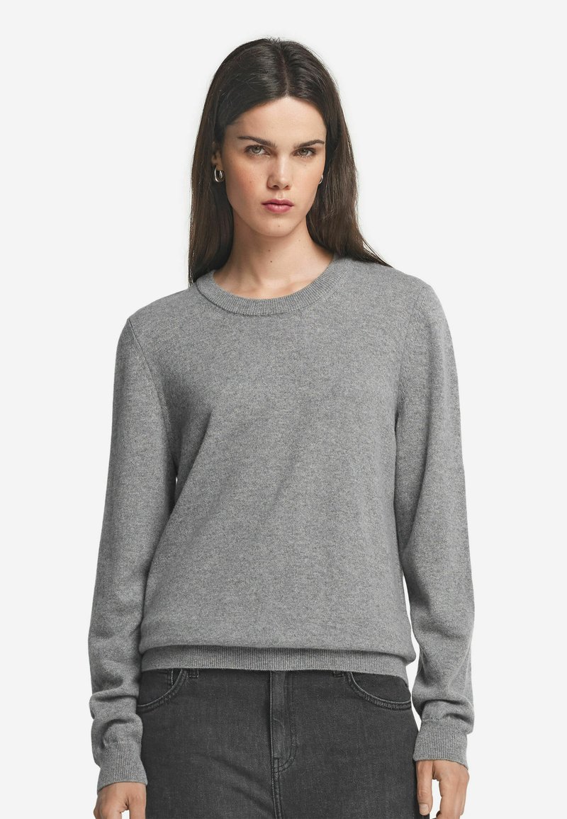 Grauer Pullover aus weichem Material, mit Rundhals, langen Ärmeln und geripptem Saum. Glatte Textur, minimalistisches Design.