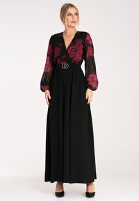 Długa czarna sukienka z przezroczystymi, kwiatowymi rękawami, głębokim dekoltem w serek, dopasowaną talią z podwójnym pierścieniem oraz zwiewnym dołem.