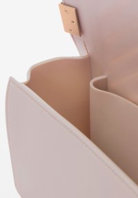 Innenraum der blush-pinken Handtasche mit glattem Material, konischer Form und einem goldfarbenen Verschluss. Zwei gebogene Fächer sind sichtbar.