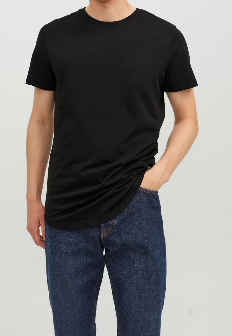 Camiseta negra de cuello redondo en algodón, de mangas cortas, corte relajado, combinada con jeans de mezclilla azul. Textura suave, diseño minimalista.