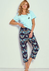 Jasnoniebieska bawełniana koszulka z kwiatową haftem w połączeniu z granatowymi spodniami w kwiatowy wzór, o luźnym kroju i elastycznym pasie.