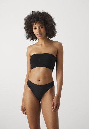 Czarny strapless crop top z marszczeniami, połączony z dopasowanymi bikini o niskim stanie. Gładka tekstura, minimalistyczny design i brak widocznych elementów metalowych.