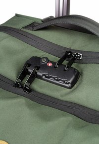 Sac à dos en tissu vert avec fermeture éclair et quincaillerie noires, doté d'une combinaison de verrouillage et de doubles fermetures éclair pour une fermeture sécurisée.