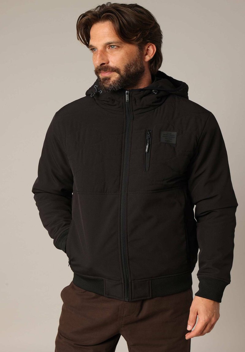 Zwarte hoodie jacket met een ritssluiting, gewatteerde textuur aan de voorkant, verstelbare capuchon en elastische manchetten. Bevat een borstzak.