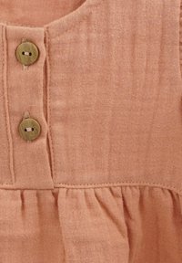 Pink linen dress with wooden buttons, featuring a rounded neckline and gathered ruffles at the hem, showcasing a textured fabric.