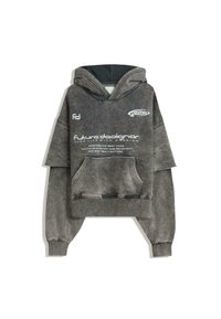 Gray oversized hoodie made of soft material, featuring a large kangaroo pocket, a drawstring hood, and printed text on the front.