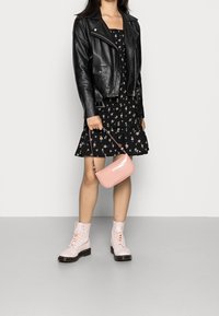 Czarna skórzana kurtka motocyklowa, czarna mini sukienka w kwiaty, różowa torebka w wzór krokodyla oraz jasnoróżowe lace-up buty wojskowe.