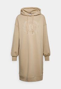 Abito felpa beige con cappuccio e polsini elasticizzati, caratterizzato da un logo ricamato tono su tono e foglie decorative attorno. Tessuto morbido.