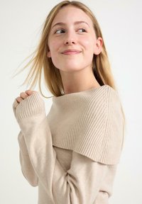 Beżowy sweter z prążkowanym kołnierzem i mankietami. Projekt charakteryzuje się miękką fakturą oraz dekoltem typu off-the-shoulder z delikatnymi detalami szwów.