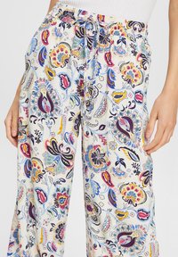 Pantalon ample pour femmes à motif floral, avec taille élastique et cordon de serrage, disponible en blanc, rose, bleu, jaune et marine.