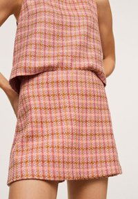 Abito a quadri rosa e arancione con texture, dotato di una parte superiore morbida e una gonna aderente. Realizzato in tessuto intrecciato, presenta una leggera lucentezza.