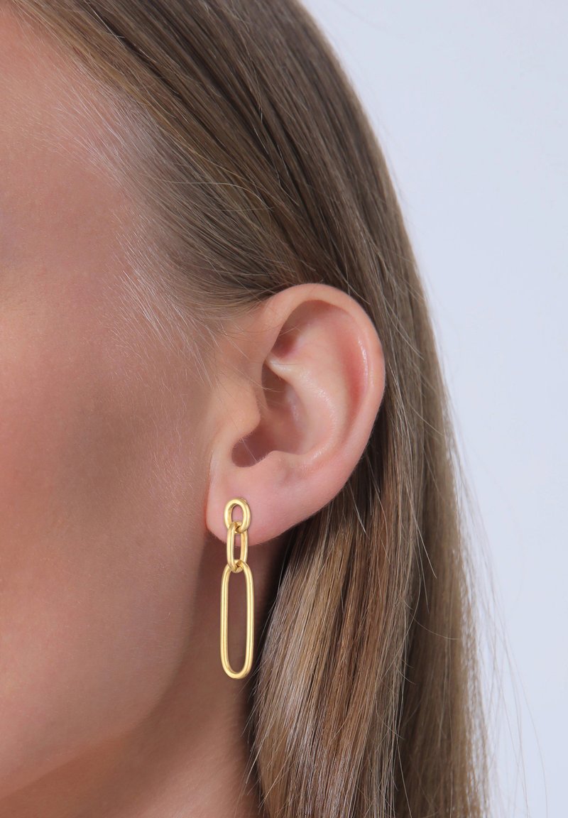 Boucles d'oreilles en chaîne dorée présentant une forme ovale allongée avec des segments enchevêtrés, mises en valeur sur un fond clair.