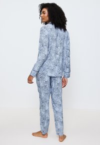Ljust blå blommönstrad pyjamasset, bestående av en långärmad knapplös topp och matchande byxor med avslappnad passform och mjuk textur.