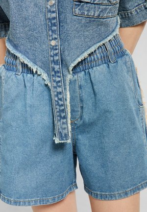 Shorts in denim con vita sfrangiata e dettagli, caratterizzati da una vestibilità comoda, colore azzurro chiaro e tasche. Tessuto dalla texture.