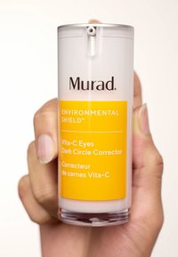 Eine transparente Flasche des Vita-C Eyes Dark Circle Corrector von Murad verfügt über ein gelbes Etikett mit schwarzem Text und einem Pumpspender oben.