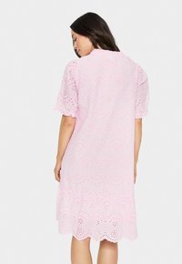 Robe en coton rose avec un ourlet festonné et une broderie à œillets, dotée de manches courtes bouffantes et d'une coupe décontractée, conçue pour le confort.