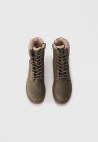 Olivgrüne Knöchelstiefel aus Wildleder, mit einem Kunstfellfutter, runder Zehenform und brauner Gummisohle sowie einem Schnürdesign.