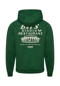 Sweat à capuche vert avec texte blanc indiquant « Bee's Stadium Restaurant » au-dessus de l'illustration du stade et « Serving the game for generations » avec le logo hummel en dessous.