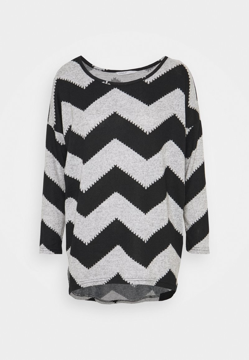 Chemise à manches longues noire et grise à motif zigzag, avec un col rond, un ourlet légèrement arrondi et une coupe ample, sur fond blanc uni.