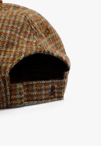 Gorra de cuadros marrones hecha de lana texturada con acentos en verde y crema; cuenta con un ala curvada y una correa ajustable en la parte posterior.