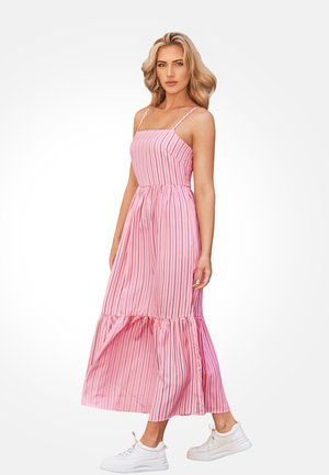 Abito maxi a righe rosa con spalline sottili, bustino aderente e orlo a balze a strati. Abbinato a sneakers bianche.