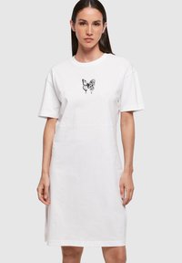 Biała bawełniana sukienka w t-shircie z krótkimi rękawami, z czarnym motylem i kwiatowym wzorem na klatce piersiowej, prosty krój, długość do kolan.