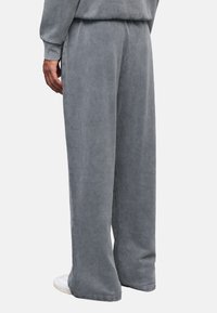 Grijze, wijde sweatpants gemaakt van zachte stof met een textuurafwerking. Beschikt over een elastische tailleband en subtiele stikdetails.