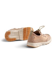 Pāris bēša krāsas ikdienas kedu ar teksturētu gumijas zoli, zamšādas un auduma virsu, kā arī pavelkšanas cilpām papēžos, novietoti uz balta fona.