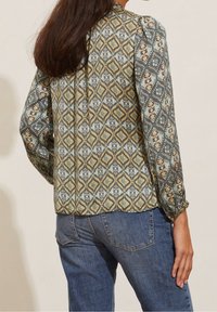 Långärmad skjorta med ett geometriskt mönster i dämpade blå, gröna och guldtoner. Lättviktig tyg med lös passform och samlade ärmar.
