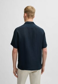 Korte mouwen overhemd van donker marineblauwe linnen, met een ontspannen pasvorm en kraag, met een gestructureerde stof en afgewerkte randen, weergegeven van achteraan.