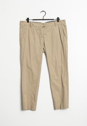 Beige casual broek met zijzakken hangend aan een zwarte hanger tegen een witte achtergrond.
