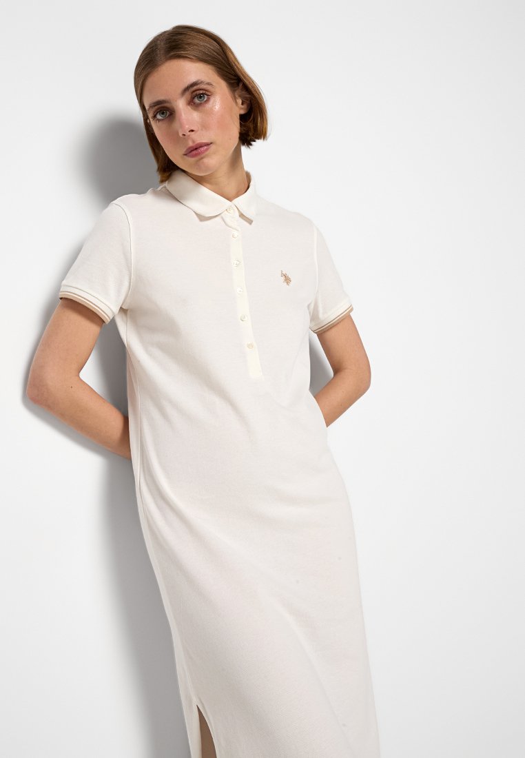 Polo jurk in lichtbeige stof, met een kraaghalslijn, korte mouwen met contrasterende afwerking, knoopsluiting aan de voorkant en zijsplitten.