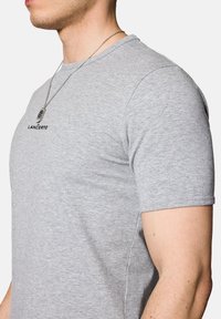 Szara koszulka typu crew neck wykonana z mieszanki bawełny. Posiada krótkie rękawy, subtelne logo na piersi oraz gładką, miękką teksturę.