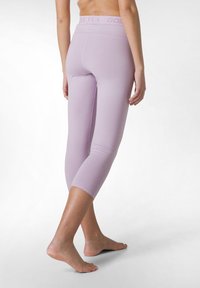 Leggings accorciati di colore viola chiaro con un ampio elastico in vita che presenta un logo discreto. Texture liscia, design aderente e taglio alla caviglia.