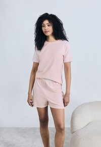 Σετ ροζ lounge που περιλαμβάνει ένα κοντομάνικο μπλουζάκι με στρογγυλή λαιμόκοψη και ταιριαστό σορτς. Κατασκευασμένο από μαλακό ύφασμα με άνετη εφαρμογή.