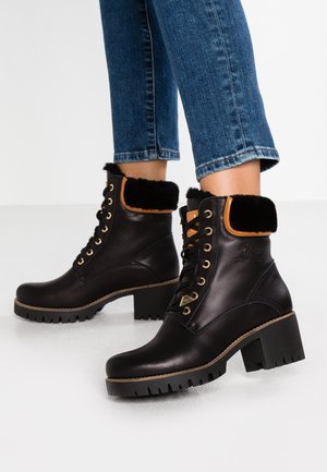 Black leather ankle boots with a chunky heel, fur-lined collar, gold eyelets, and black laces; textured sole with treads for grip.