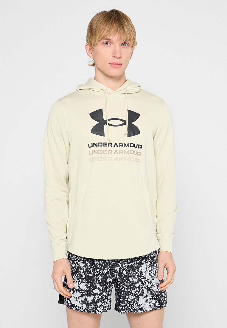 Felpa con cappuccio di un beige chiaro con logo e testo neri di Under Armour. Abbinate a pantaloni corti a pois bianchi e neri. Abbigliamento sportivo casual.