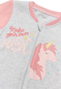 Sudadera gris con cremallera y mangas rosas. Presenta un diseño de unicornio bordado y el texto "Crea tu propia MAGIA" con estrellas en colores pastel.