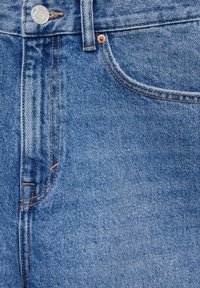 Ljust blå denimjeans med en klassisk femficksdesign, med orange sömmar och metallknappstängning. Slät textur med subtil slitage.