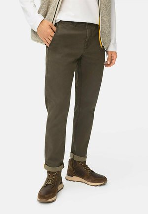 Olive green trousers with a straight cut, featuring rolled hems, made from soft cotton blend fabric. Paired with brown lace-up boots.
