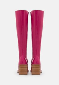 Różowe, błyszczące skórzane kozaki do kolan na masywnym, drewnianym obcasie. Posiadają zamek błyskawiczny z tyłu i gładką, elegancką teksturę.
