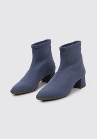 Bottines à cheville bleues avec un bout pointu, en tissu texturé, et un large talon carré. Présente un design sans couture et des détails de couture minimalistes.
