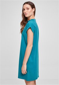 Robe t-shirt oversize en teal en coton. Présente des manches courtes et un col rond, avec une coupe décontractée. Texture douce.