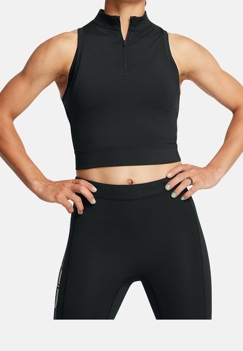Czarny sportowy crop top z wysokim kołnierzem i krótkim zamkiem; zestawiony z czarnymi legginsami o wysokim stanie z bocznymi akcentami.